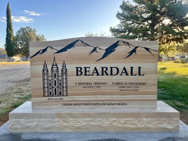Custom monument with mountain design and engraved names in a park setting.